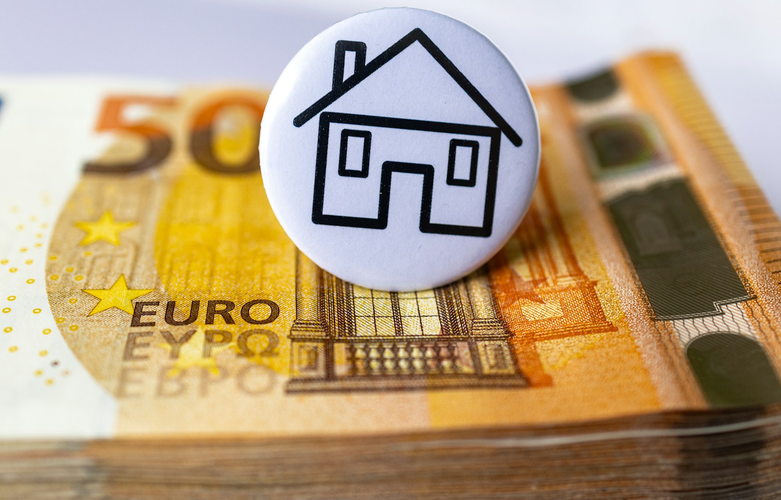 a button with a house on top of a stack of money