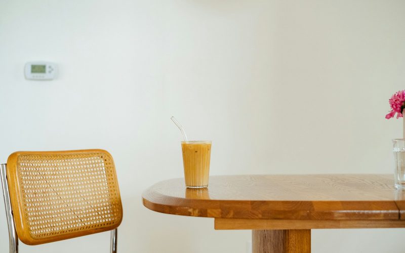 a table with a chair and a vase with a flower